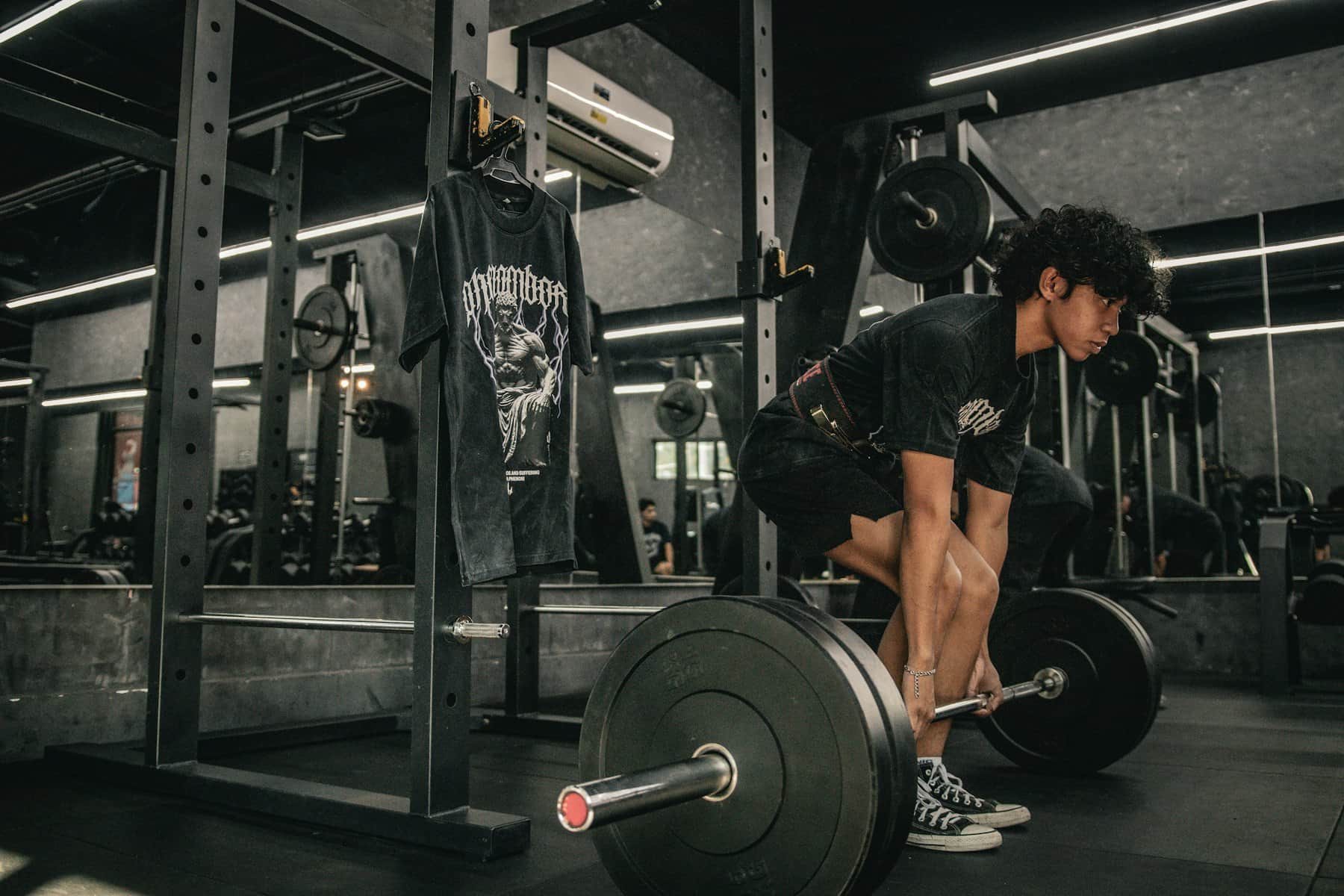 Lifter crouched at a loaded barbell setting up a deadlift in a dark gym