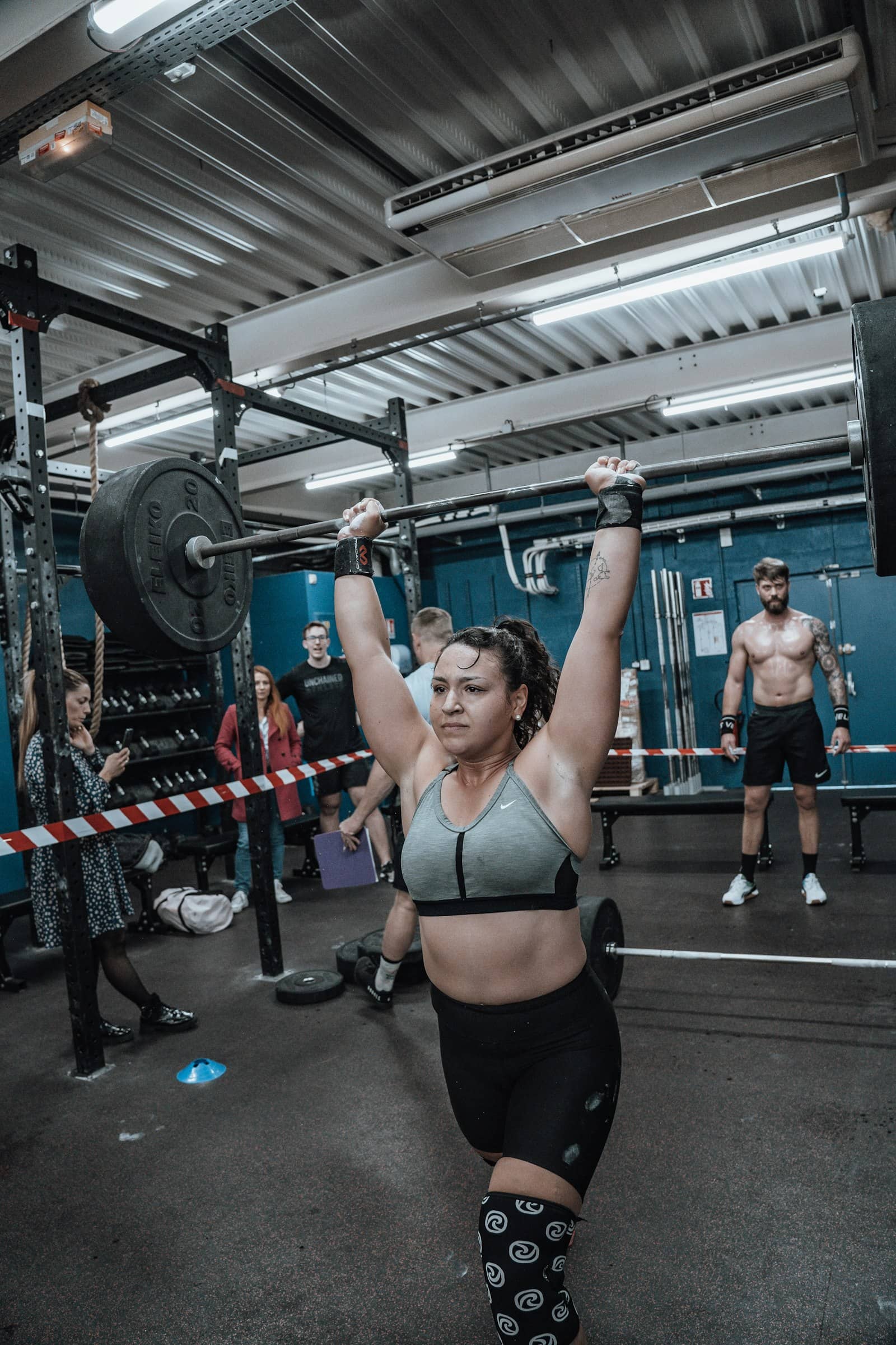 A member catches a heavy clean at the chest while the rest of the class watches from behind