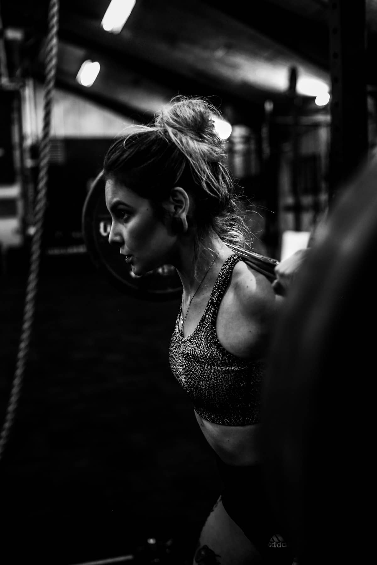 Lifter focused under the bar in a squat rack, photographed in black and white