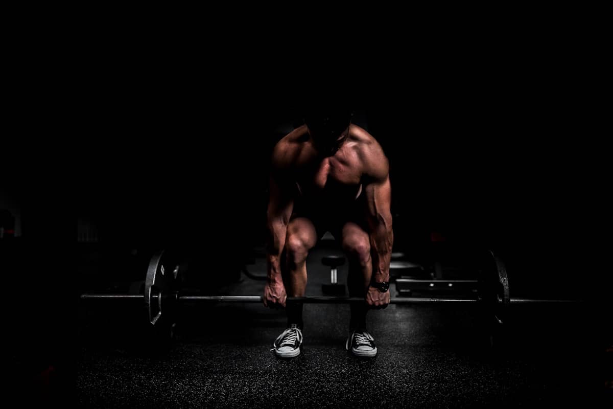 Lifter crouched over a loaded barbell in a dark gym, ready to pull