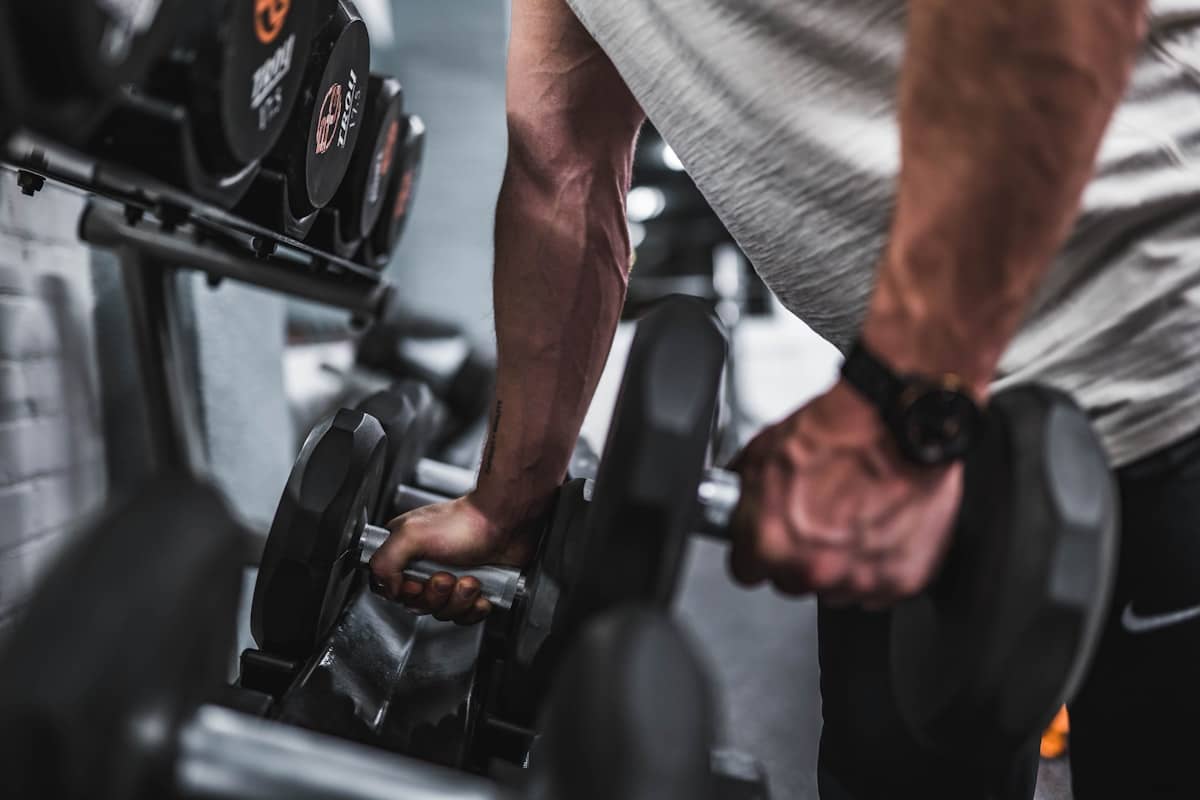 Lifter picking a pair of dumbbells off the rack mid-session